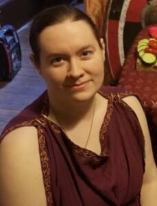 a woman dressed in a simple brown tunic with woven trim